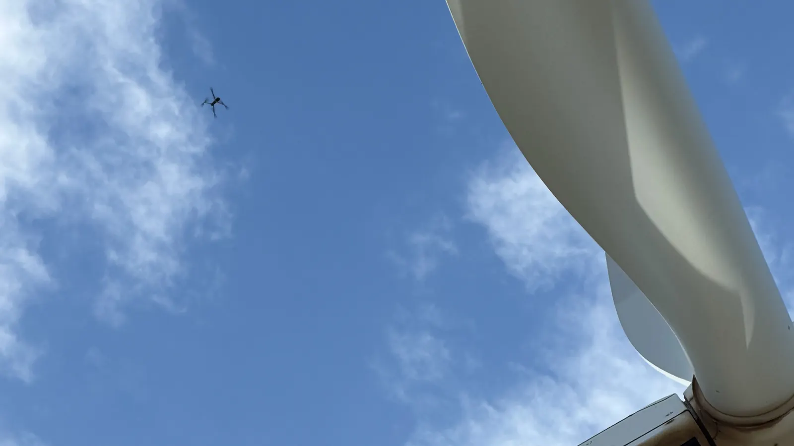 Drone Force inspection drone inspecting a wind turbine beside the nacelle and blade under a blue sky